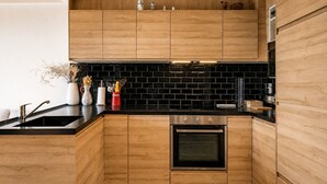 A modern kitchen with wooden cabinets, a black backsplash, and stainless steel appliances. - Stunning apartment with breathtaking view! (Huez)