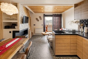 Una cocina moderna con encimera de madera, estufa integrada y comedor con mantel rojo y blanco.