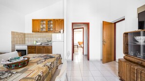 A kitchen with wooden cabinets, a stove, and a dining area with a table and chairs. - Stunning apartment in Sibenik with WiFi (Sibenik)