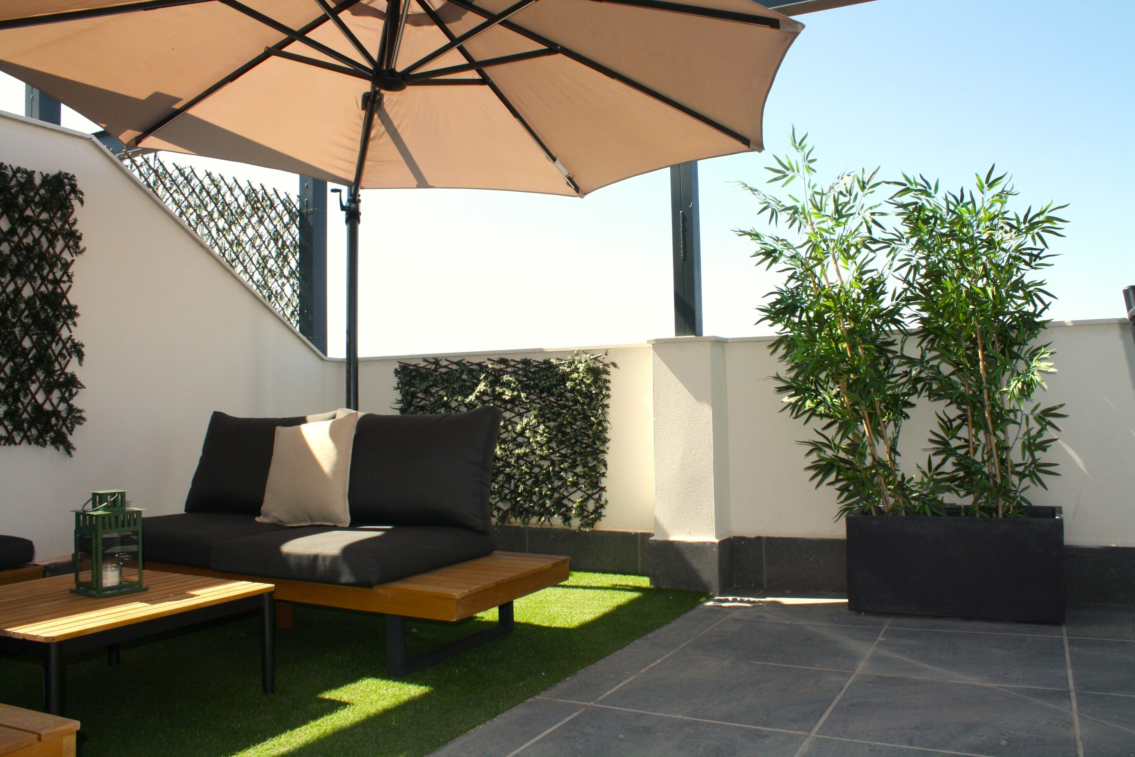 Un espace extérieur aménagé avec un canapé, une table et un parasol.