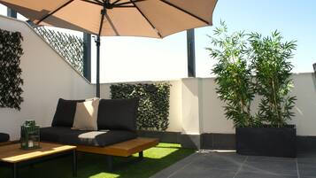 Un espace extérieur aménagé avec un canapé, une table et un parasol.