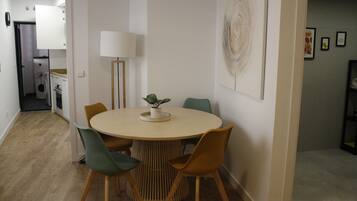 Comedor con una mesa redonda, cuatro sillas, una lámpara y una obra de arte colgada en la pared.