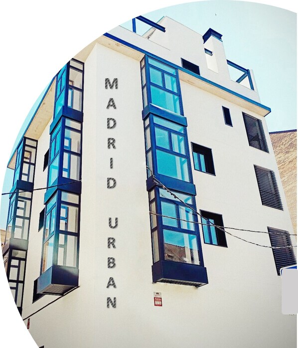 En moderne bygning med teksten "MADRID URBAN" på facaden, med flere vinduer og altaner.