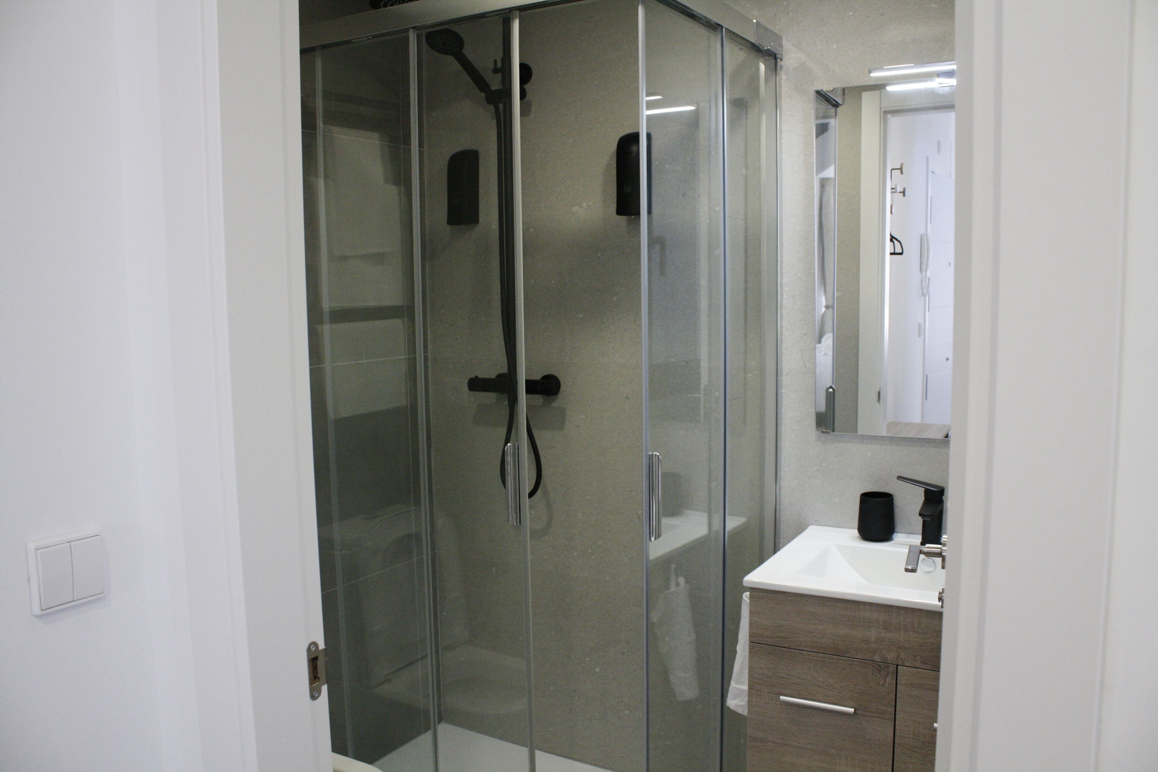 A modern bathroom with a glass-enclosed shower, a white sink, and a mirror above the sink.