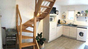Une cuisine moderne avec un escalier en bois, des appareils électroménagers intégrés et un petit coin repas.