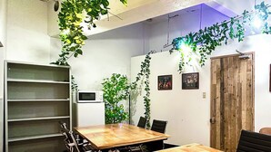 A conference room with a wooden table, black chairs, a whiteboard, and green plants. - 202】 【7:00 IN/19:00 OUT】4min丨Nearby Shinjuku and Kabukicho area by train丨Only bath and kitchen丨Maximum 3 persons (Nakano City)