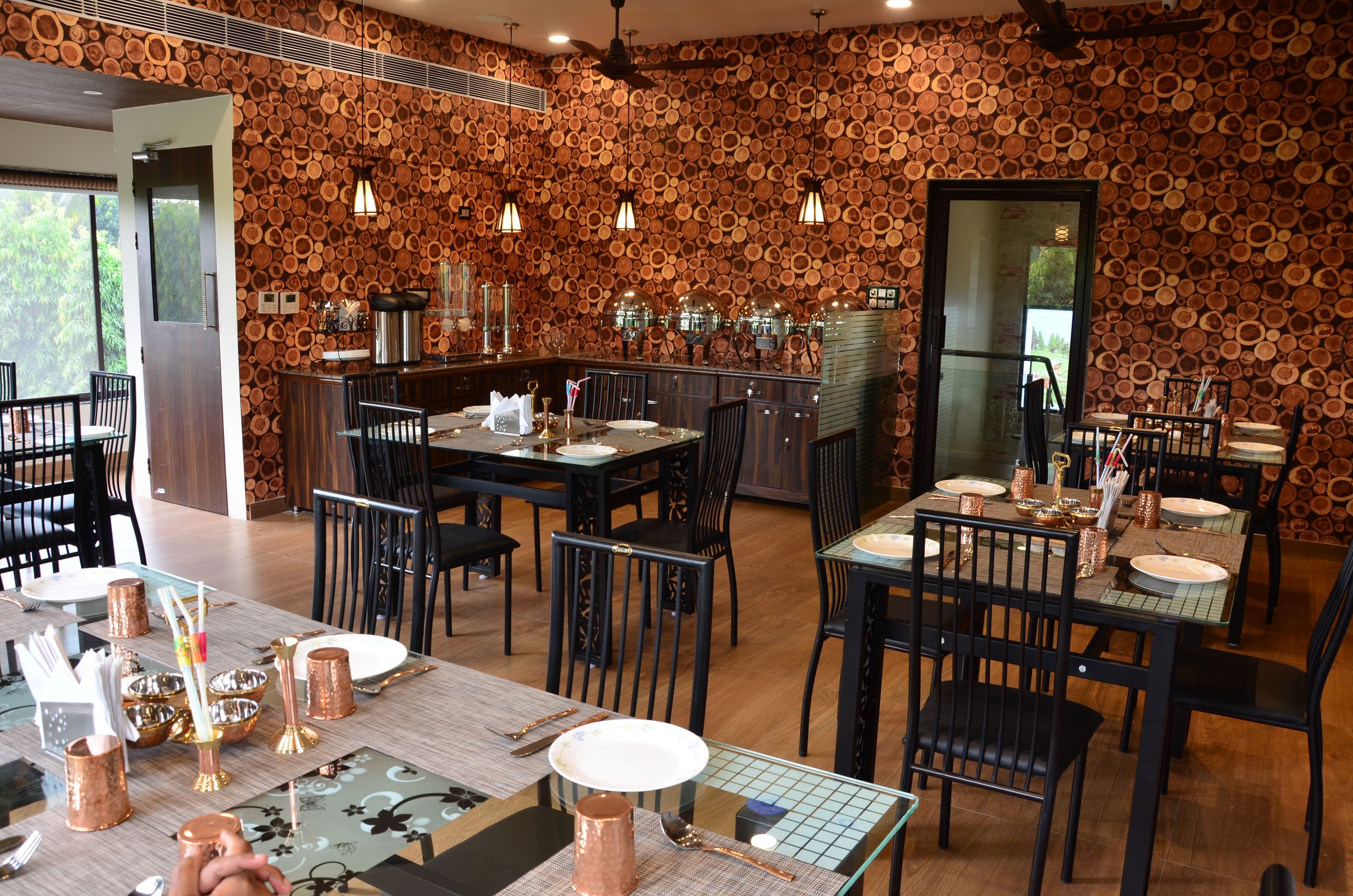 Ein Restaurant mit rustikalem Holzwanddesign, mehreren Esszimmertischen mit Stühlen und einer Bar.