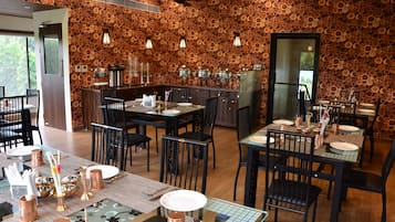 Ein Restaurant mit rustikalem Holzwanddesign, mehreren Esszimmertischen mit Stühlen und einer Bar.