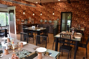 Ein Restaurant mit rustikalem Holzwanddesign, mehreren Esszimmertischen mit Stühlen und einer Bar.