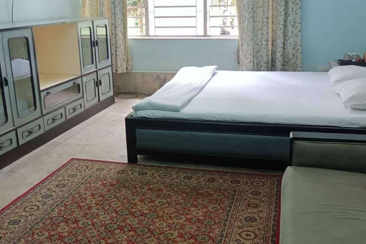 Ein Schlafzimmer mit einem Bett, einem Schlafsofa, einem Schrank und einem Teppich mit Muster.