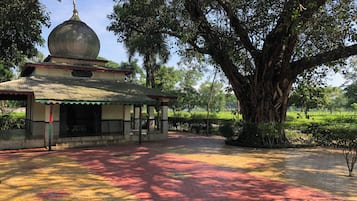 A traditional building with a dome roof, surrounded by lush greenery and a paved walkway.