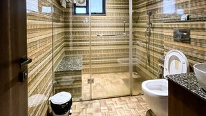 Een moderne badkamer met een douchecabine van glas, een toilet en een wastafel.