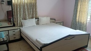 Een slaapkamer met een bed, nachtkastjes, een spiegel en gordijnen.