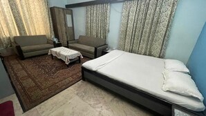 Een slaapkamer met een enkel bed, een slaapbank, een klein tafeltje en een kledingkast.