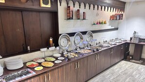A buffet setup with various food items and serving utensils. - Hotel Maple Ridge  (Agra)