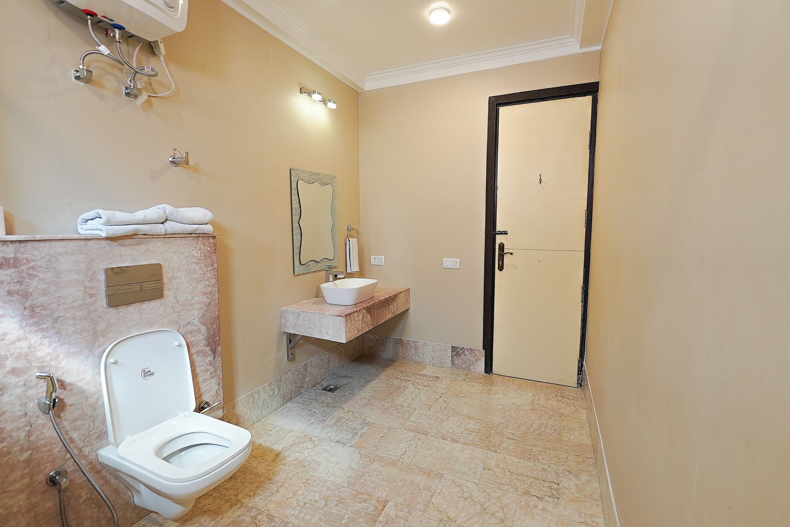 A bathroom with a toilet, sink, mirror, and tiled floor.