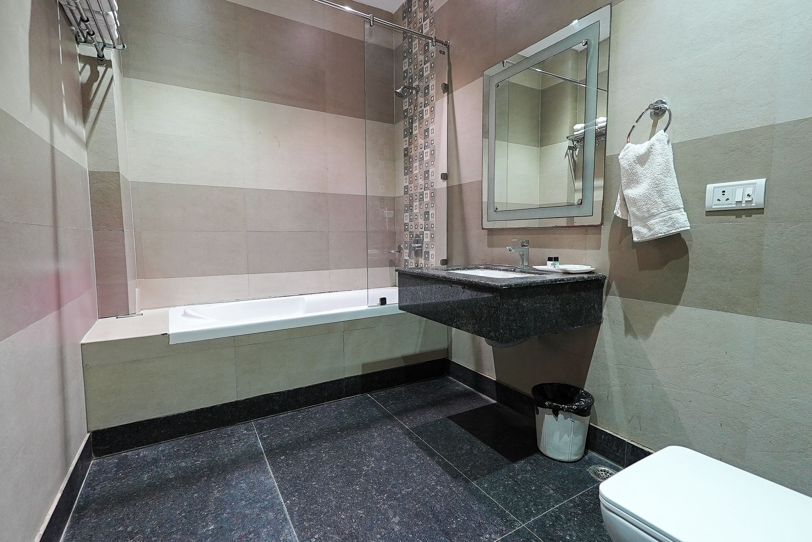 A bathroom with a bathtub, a sink, a mirror, and a towel rack.