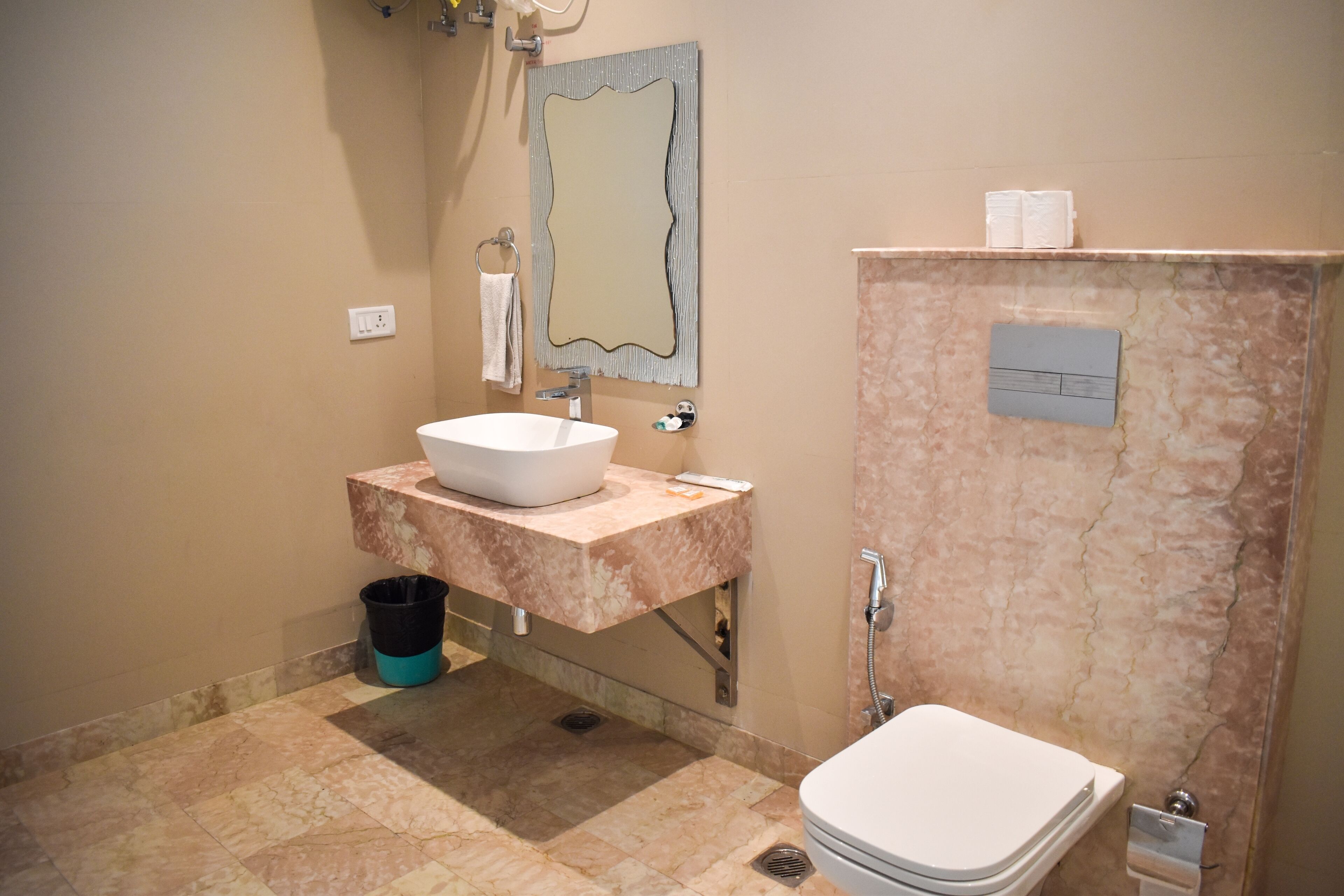 A bathroom with a white sink, marble countertop, and a toilet.