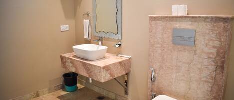 A bathroom with a white sink, marble countertop, and a toilet.