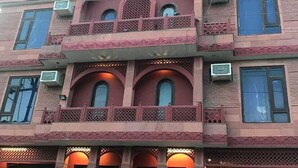 A multi-story building with a traditional architectural style, featuring balconies, arched windows, and decorative lattice work. - Hotel Maple Ridge  (Agra)