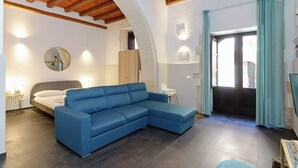 Ein modernes Wohnzimmer mit einem blauen Ecksofa, einem Bett und einer Holzbalkendecke.