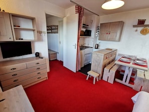 A compact, well-organized room with a television, wooden furniture, a kitchenette, and a dining area. - Superior studio cabin near slopes, sleeps 4, south balcony, ski locker (Les Adrets-Prapoutel)