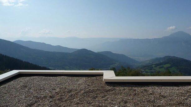 Vista panorâmica de uma paisagem montanhosa a partir de um ponto alto, provavelmente um terraço ou mirante.