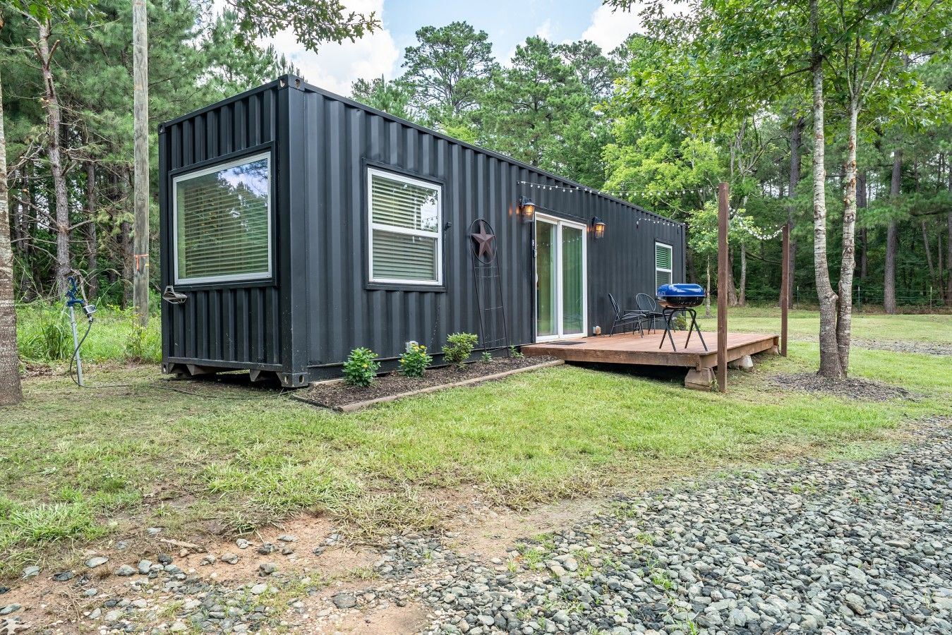 Eine kompakte, moderne Holzhütte mit Terrasse, eingebettet in eine natürliche Landschaft.