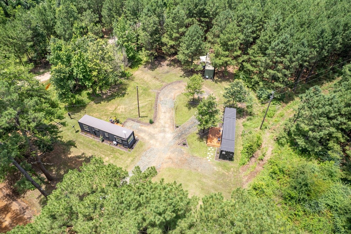 An aerial view of a property with a large building, a smaller structure, and a paved area with a pathway.