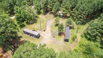 An aerial view of a property with a large building, a smaller structure, and a paved area with a pathway.