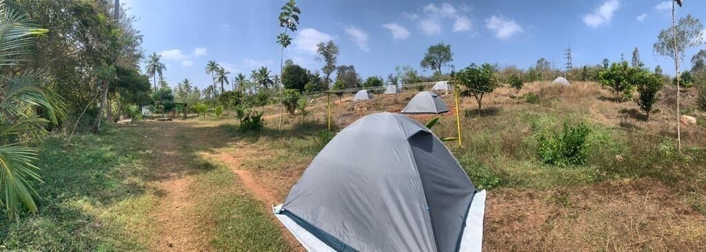 A tent set up on a grassy hill with a clear sky.
