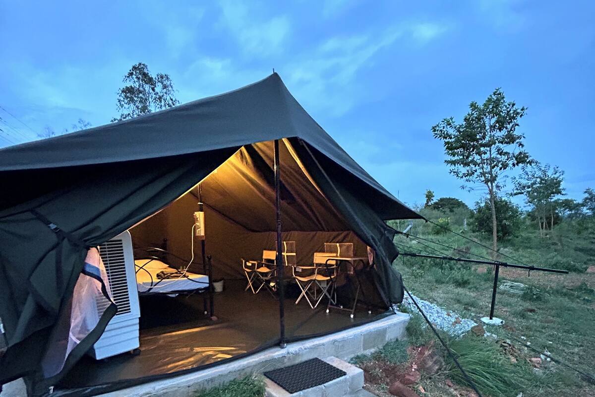 Uma tenda com uma cama, uma mesa e cadeiras no interior.