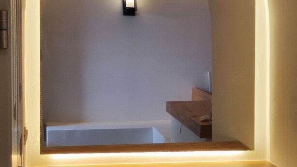 A modern kitchen with a wooden countertop, a built-in oven, and a wall-mounted light fixture.