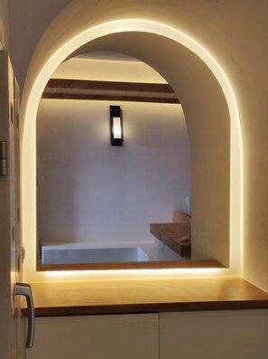 Una cocina moderna con encimera de madera, horno empotrado e iluminación en la pared.