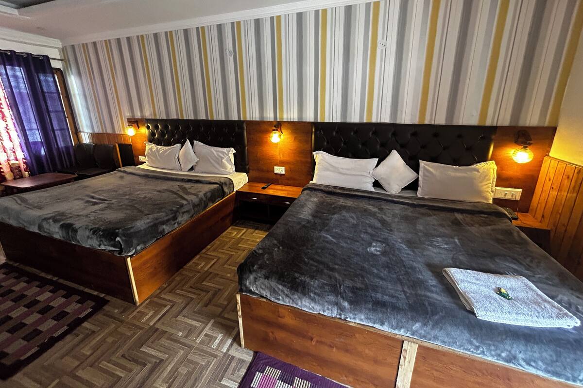 A hotel room with two beds, wooden headboards, striped curtains, and a ceiling fan.