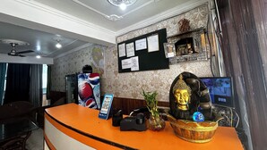 A hotel reception area with a counter, a map on the wall, a Buddha statue, and a security camera. - Hotel Honey N Spice (Dharamshala)
