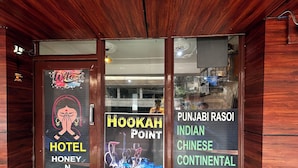 A hotel entrance with a wooden facade, a sign reading "HOOKAH POINT" and "PUNJABI RASOI INDIAN CHINESE CONTINENTAL". - Hotel Honey N Spice (Dharamshala)