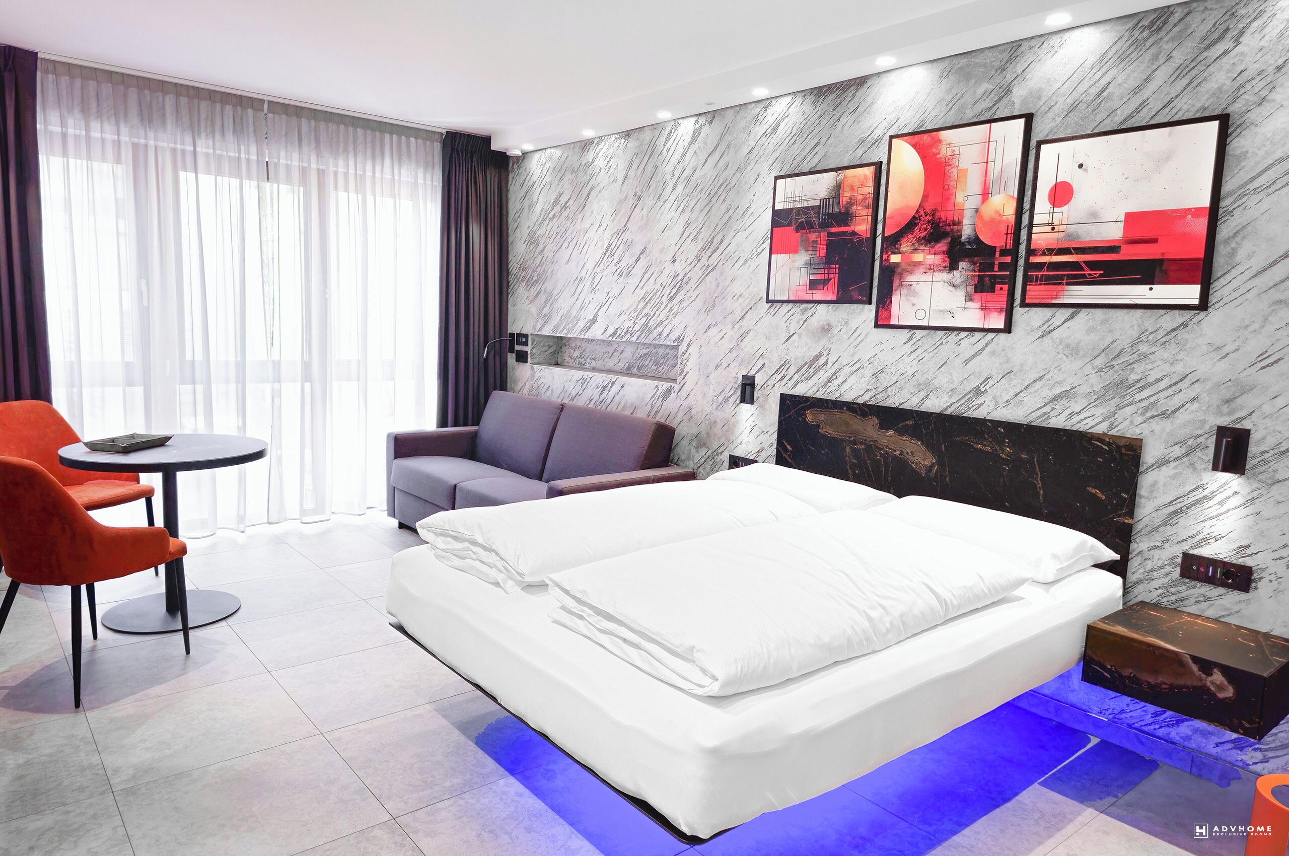 Una habitació d'hotel moderna amb un llit gran, una zona de seients amb una taula i obres d'art a les parets.