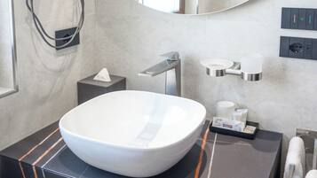 Un bagno moderno con un lavabo bianco a incasso, un soffione a mano, un porta asciugamani e un dispenser per sapone sul piano di lavoro.