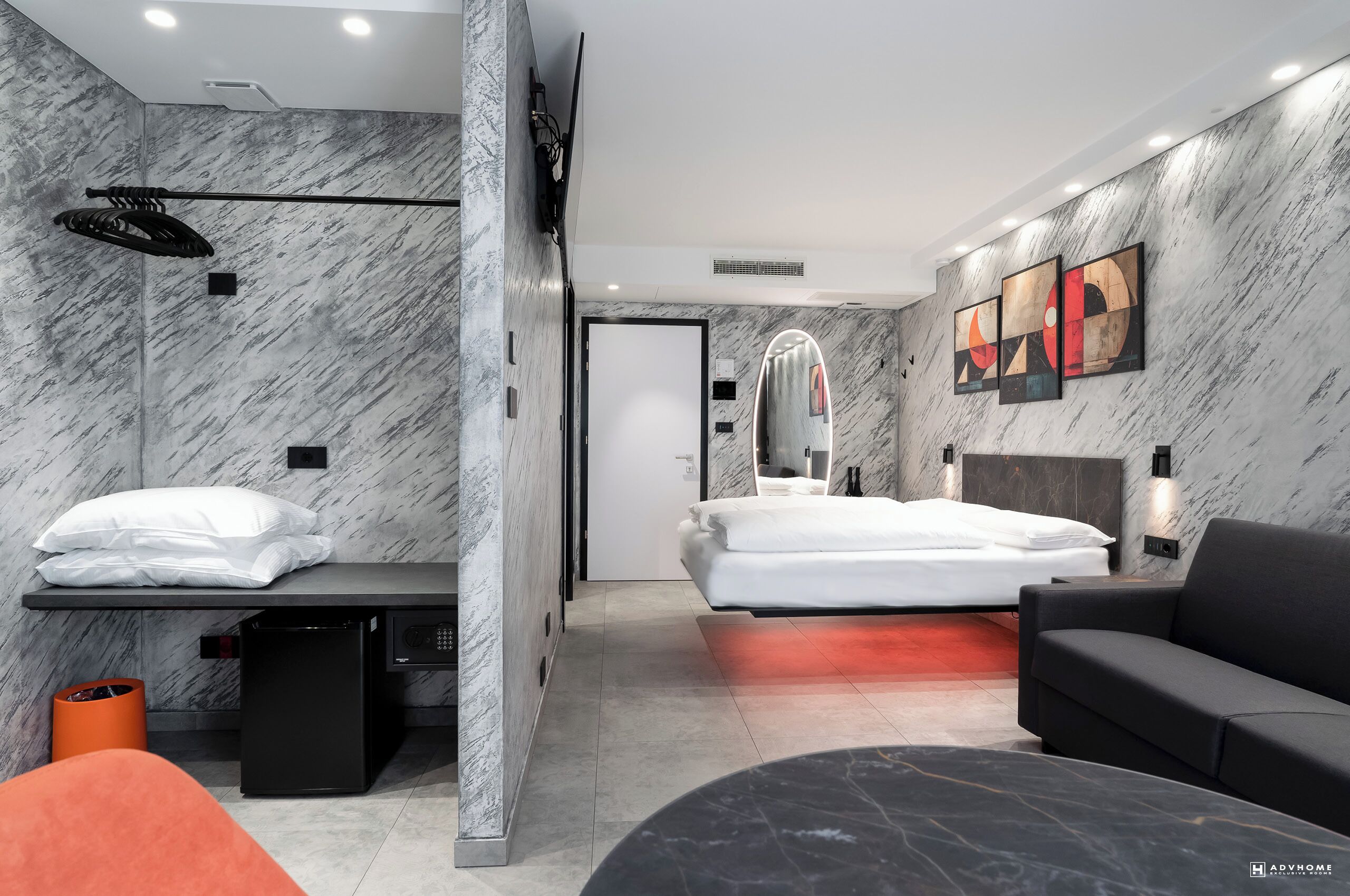 Una habitación de hotel moderna con pared de mármol, una cama, un sofá, un escritorio y un televisor.