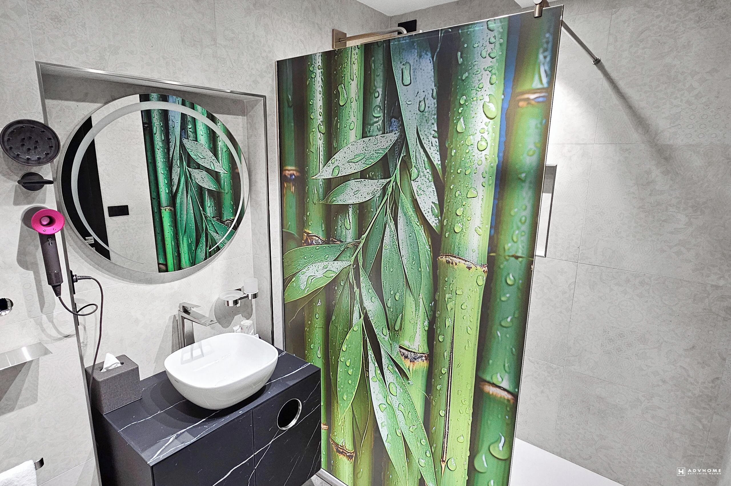 A bathroom with a round mirror, a white sink, and a shower curtain with a bamboo leaf design.