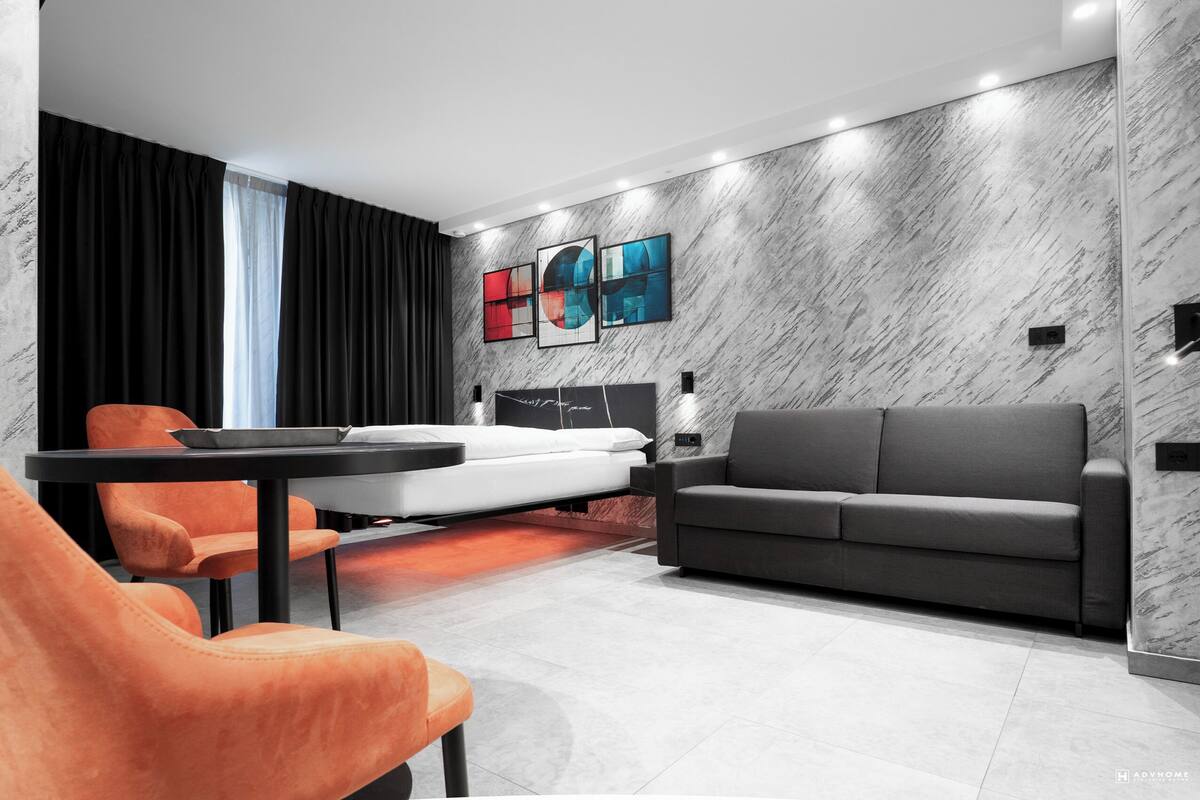 A modern living room with a sofa, a dining table, and orange chairs.