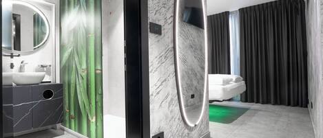 A modern bathroom with a large mirror, a white sink, and a shower area.