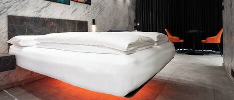 Una camera da letto moderna con un letto grande, una testiera in marmo e opere d'arte alle pareti.