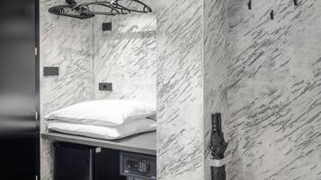 Un bagno con parete in marmo, lavabo, asciugamano e zona doccia.