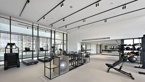 Een moderne fitnessruimte met cardioapparatuur, losse gewichten en een spiegelwand.