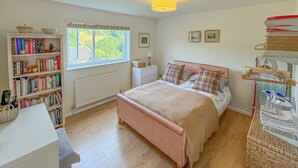 Une chambre à coucher avec un lit, une bibliothèque, une fenêtre et un radiateur.