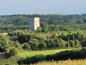 A tower surrounded by dense greenery and a hilly landscape. - Tranquil Carney Commons Cottage - Sleeps 10 (Congor)