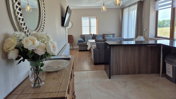 A modern living room with a large mirror, a sofa, a coffee table, and a TV mounted on the wall. - Tranquil Carney Commons Cottage - Sleeps 10 (Congor)