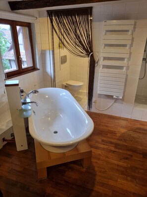 Ein Badezimmer mit freistehender Badewanne, Toilette und Duschbereich.